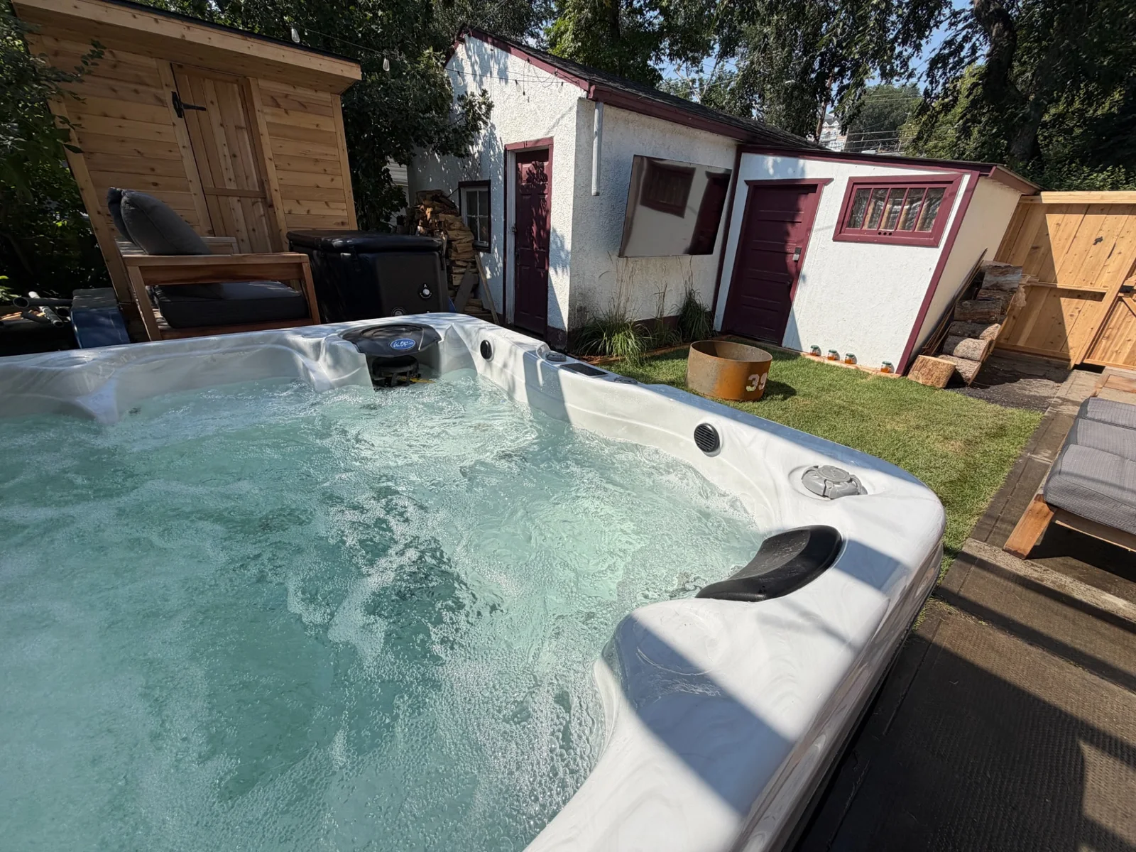 Bubbling hot tub with the sauna and backyard buildings at Merlot House