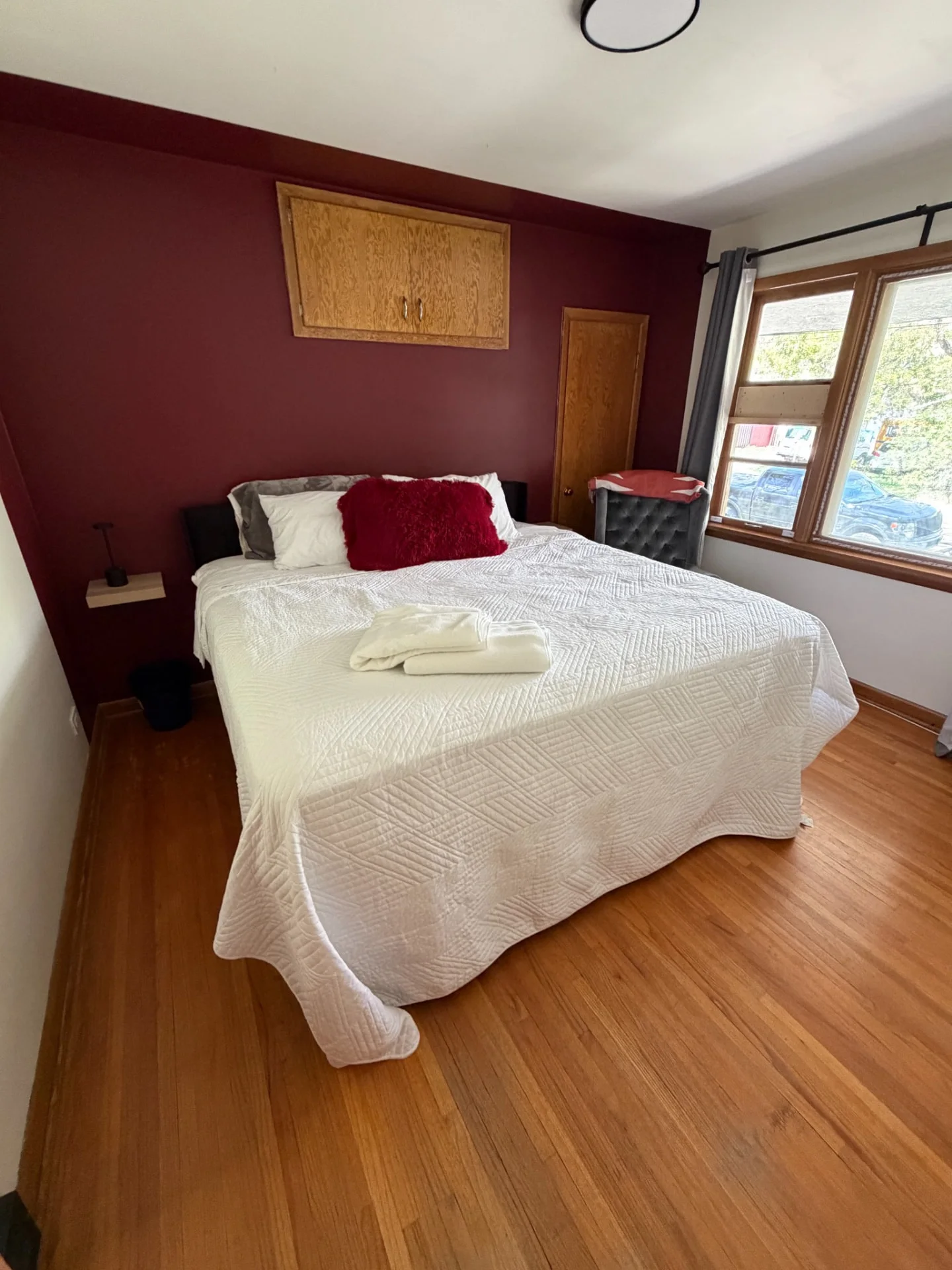 Merlot House bedroom view with white bedding and burgundy accent wall