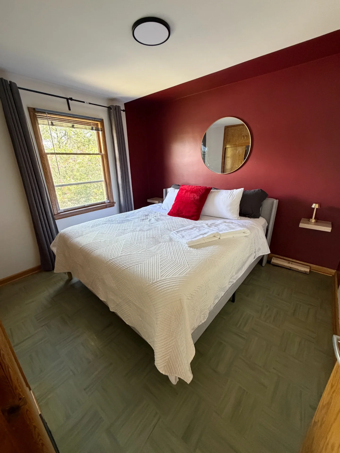 Merlot House bedroom with white bedding, burgundy accent wall and window